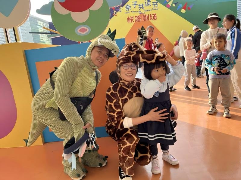 Li Wen, initiator of Parent-Child Reading Day, dressed as the giraffe from the picture book Move in and move out, during the "Day of Love’s Return" commemorative event.