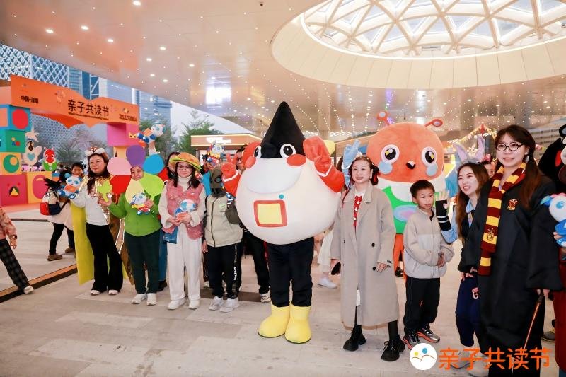 Festival mascot “Koko Bird” parading with costumed parent-child participants.